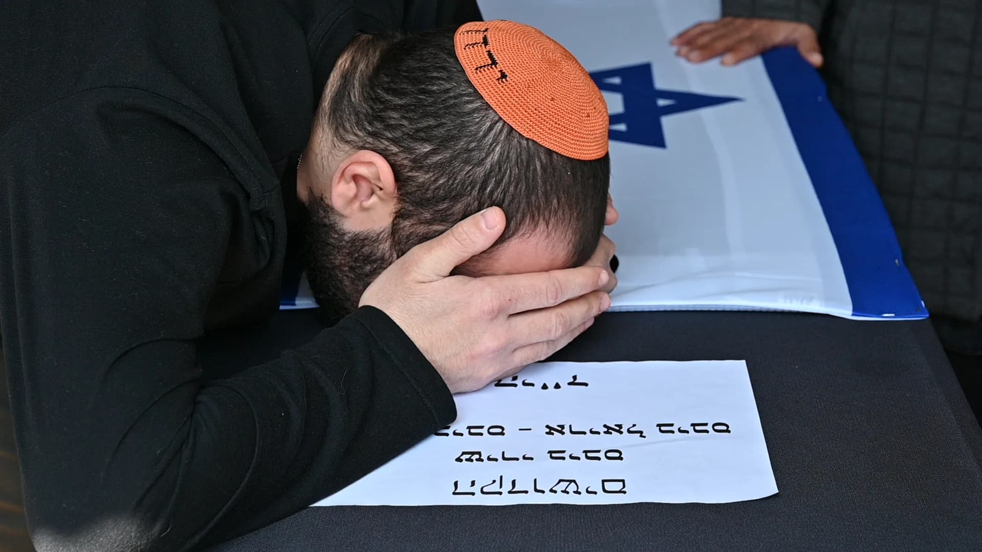 גבר מרכין את ראשו ודגל ישראל מאחוריו