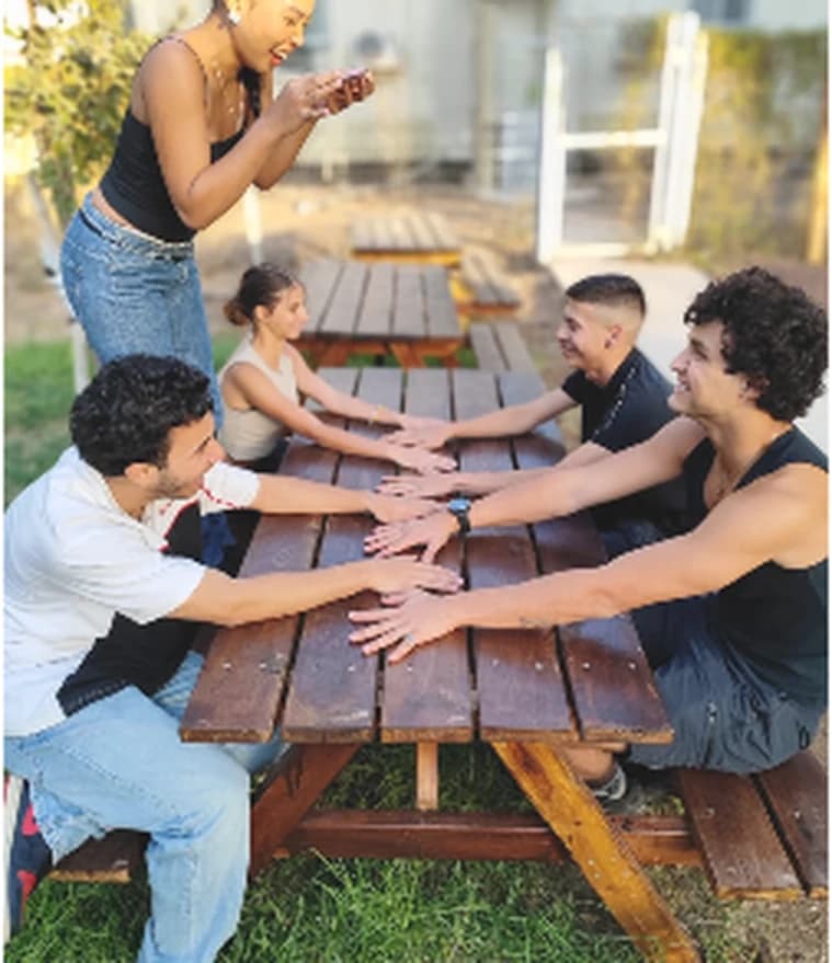 משתתפים מושיטים ידיים זה לזה סביב שולחן פיקניק
